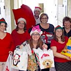 Nelson Mullins employees dressed in Xmas outfits holding Xmas gifts.