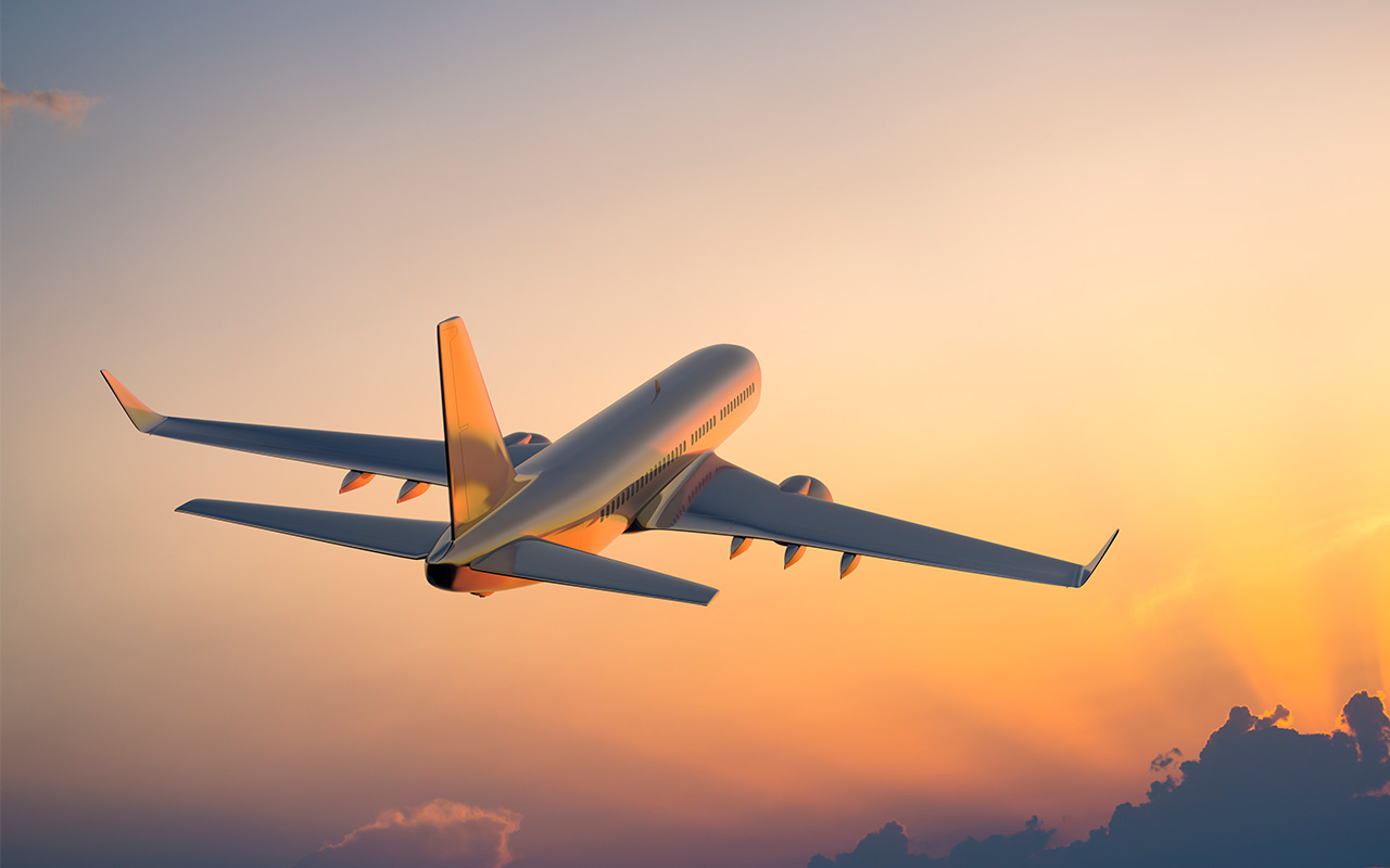 Passenger airplane flying above clouds during sunset
