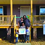 Photo of a family in front of their new home